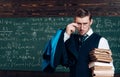 Young professor holding pile of books looking over his glasses. Aristocrat scholar in elite college Royalty Free Stock Photo