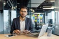A young programmer in a suit smiles while working in a modern office environment, ready for business and efficiency. Royalty Free Stock Photo