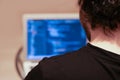 Young programmer writes code in a programming language on a laptop. The view from the back. Blurred background and copy space. Royalty Free Stock Photo