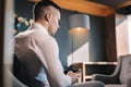 Young but prosperous businessman sitting in his office using phone