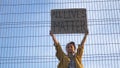 Young protesting woman standing behind the fence holds a poster - All Lives Matter