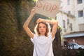 Young protesting woman in white shirt and jeans holds protest sign broadsheet placard with slogan `Stop` for public