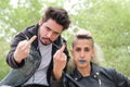 Young punk couple flipping the bird to the camera in a park Royalty Free Stock Photo