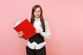 Young puzzled concerned business woman in glasses holding red folder for papers document looking down on pink Royalty Free Stock Photo