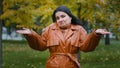 Young puzzled upset hispanic woman standing outdoors in park shrugging shoulders doubtful looking at camera unsure does Royalty Free Stock Photo