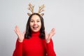 Young rapturous woman with christmas deer antlers on white background