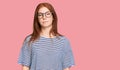 Young read head woman wearing casual clothes and glasses relaxed with serious expression on face Royalty Free Stock Photo