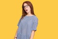 Young read head woman wearing casual clothes and glasses in shock face, looking skeptical and sarcastic, surprised with open mouth Royalty Free Stock Photo