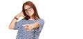 Young read head woman wearing casual clothes and glasses smiling doing talking on the telephone gesture and pointing to you Royalty Free Stock Photo