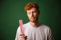Young readhead beardy man looking at pink comb Royalty Free Stock Photo