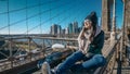 Young and reckless girl sits on the rim of Brooklyn Bridge New York