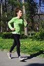 Young red hair lady in green shirt doing her run training in the park