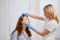 A young red-haired beautiful girl undergoes a medical examination in a cosmetology clinic. A female dermatologist