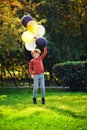 Young red-haired boy playing with a bunch of yellow white black balloons in the Park Royalty Free Stock Photo