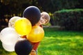 Young red-haired boy playing with a bunch of yellow white black balloons in the Park Royalty Free Stock Photo