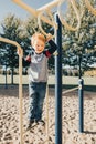 Young red-haired Caucasian boy hanging on monkey bars in park on playground. Summer outdoors activity for kids. Active preschool Royalty Free Stock Photo