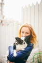 A young red-haired Caucasian woman holds a small funny dog in the arms of two colors of black and white chihuahua. Hugs and kisses Royalty Free Stock Photo