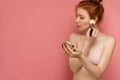 Young red-haired female wearing lace bra makes up her cheekbones with a make-up brush Royalty Free Stock Photo