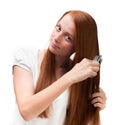 Young red-haired girl combing her long hair. Isolated on white b Royalty Free Stock Photo
