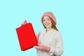 Young red-haired girl with gift bags after shopping on a blue background looking towards the camera Royalty Free Stock Photo