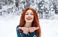 Young red-haired girl with long red hair on a winter background.Air kiss. Red-haired woman in a summer dress on the background of Royalty Free Stock Photo