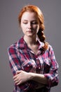 Young red-haired girl with a pigtail in a plaid shirt