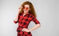 Young red-haired girl in a red checkered shirt. Young girl in red glasses.