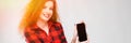 Young red-haired girl in a red checkered shirt. Young girl shows phone