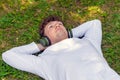 Young red-haired man in headphones lies on the green grass Royalty Free Stock Photo