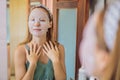 Young red-haired woman doing facial mask sheet. Beauty and Skin Care Concept Royalty Free Stock Photo