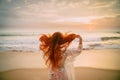 Young red-haired woman with flying hair on the ocean, rear view Royalty Free Stock Photo