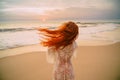 Young red-haired woman with flying hair on the ocean, rear view Royalty Free Stock Photo