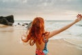 Young red-haired woman with flying hair on the ocean, rear view Royalty Free Stock Photo