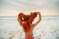 Young red-haired woman with flying hair on the ocean, rear view Royalty Free Stock Photo