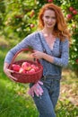 Young red-haired woman helps with picking apples