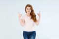 Woman points her fingers up while standing on a light background