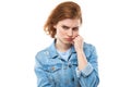 The young red-haired woman pondered. Resentment and disappointment. Girl model in a blue denim jacket on a white background. I