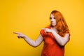 Young red haired woman shows point gesture