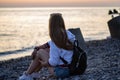 Young red-haired woman sitting on the rocks and watching at the sunset on the sea Royalty Free Stock Photo