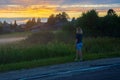 A young red-haired woman on a summer evening looks at the rural landscape. Fog over a field in the village. Shallow depth of field