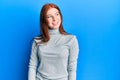 Young red head girl wearing turtleneck sweater looking to side, relax profile pose with natural face and confident smile