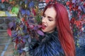 Young Red head gothic woman acting goofy and munching autumn leaves surrounded by vines