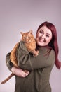 Woman holding cute male orange tabby cat smiling