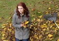Young red-heaired woman outiside on fall day - raking leaves Royalty Free Stock Photo
