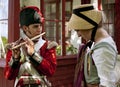 Young redcoat soldier playing flute for a young girl