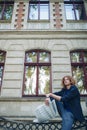 Young reddish man reading newspaper near old style building