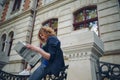 Young reddish man reading newspaper near old style building