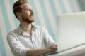 Young redhair man working on laptop in room by the blue striped