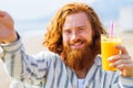 young redhaired ginger bearded man working outdoors in sea cafe with laptop an summer day