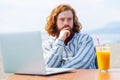 young redhaired ginger bearded man working outdoors in sea cafe with laptop an summer day